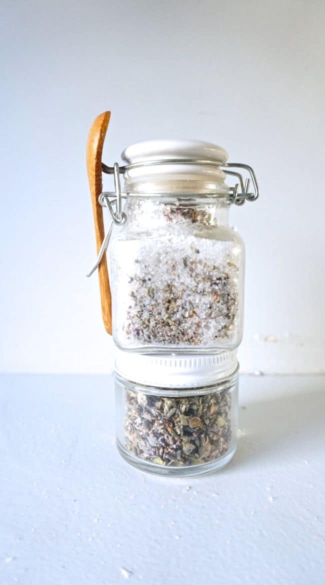 A jar of homemade bath salts on top of a jar of dried lavender. 