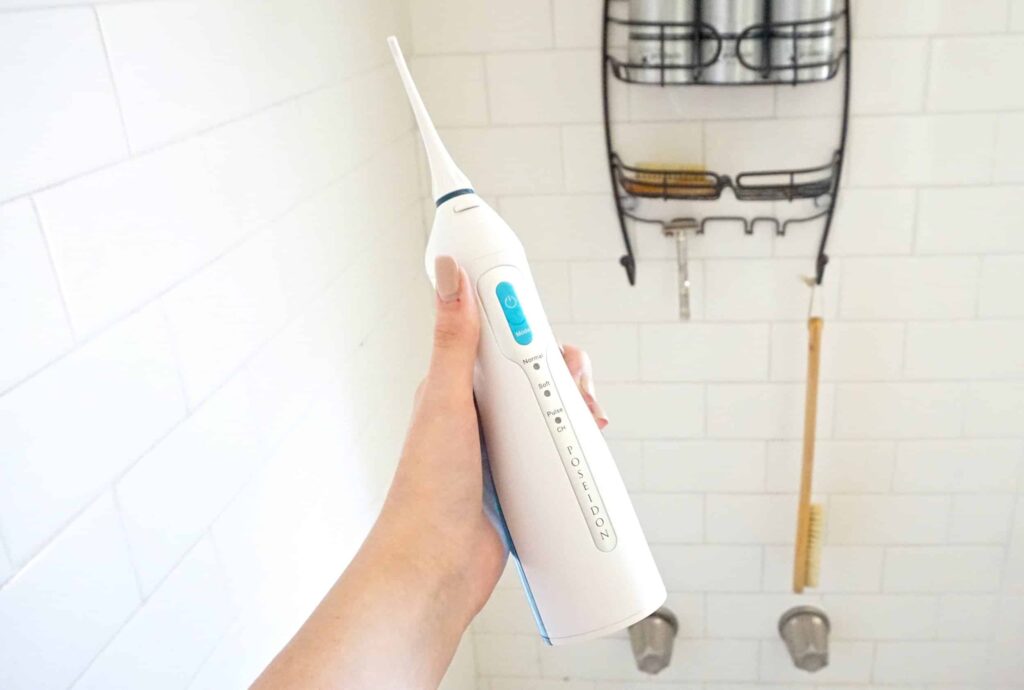 a hand holding a water flosser in a shower