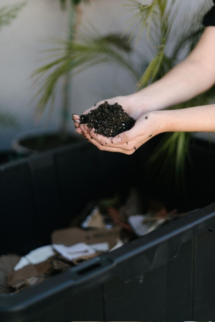 holding soil in hands over diy compost bin