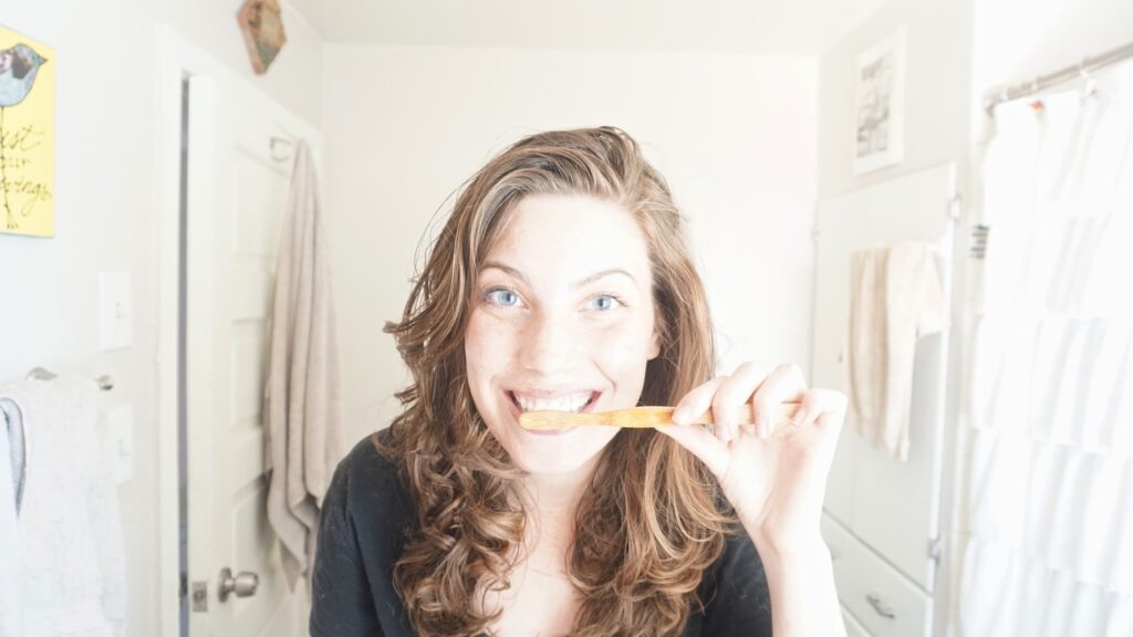 woman brushing her teeth with a DIY tooth powder