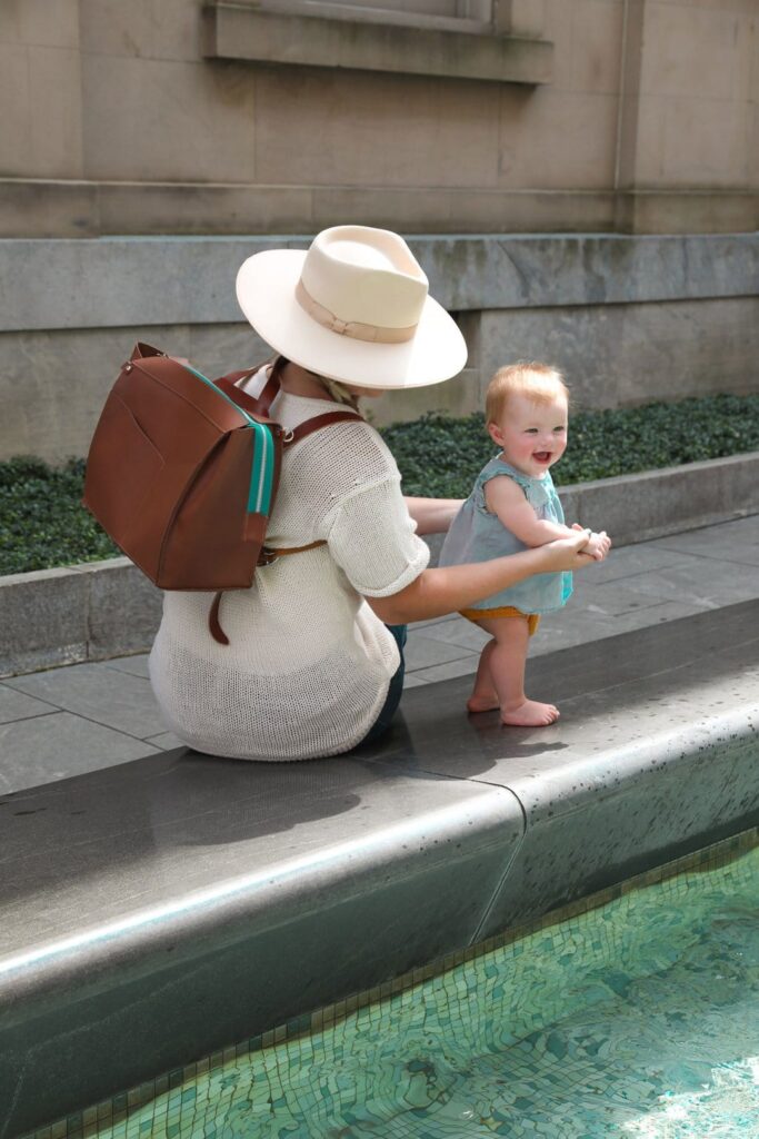 woman wearing a sustainable backpack diaper bag and her child - the best gift for new parents.