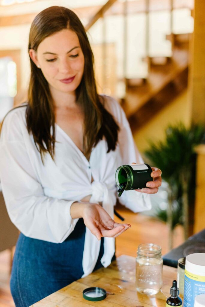 Woman shaking some sustainable vitamins into her hand.