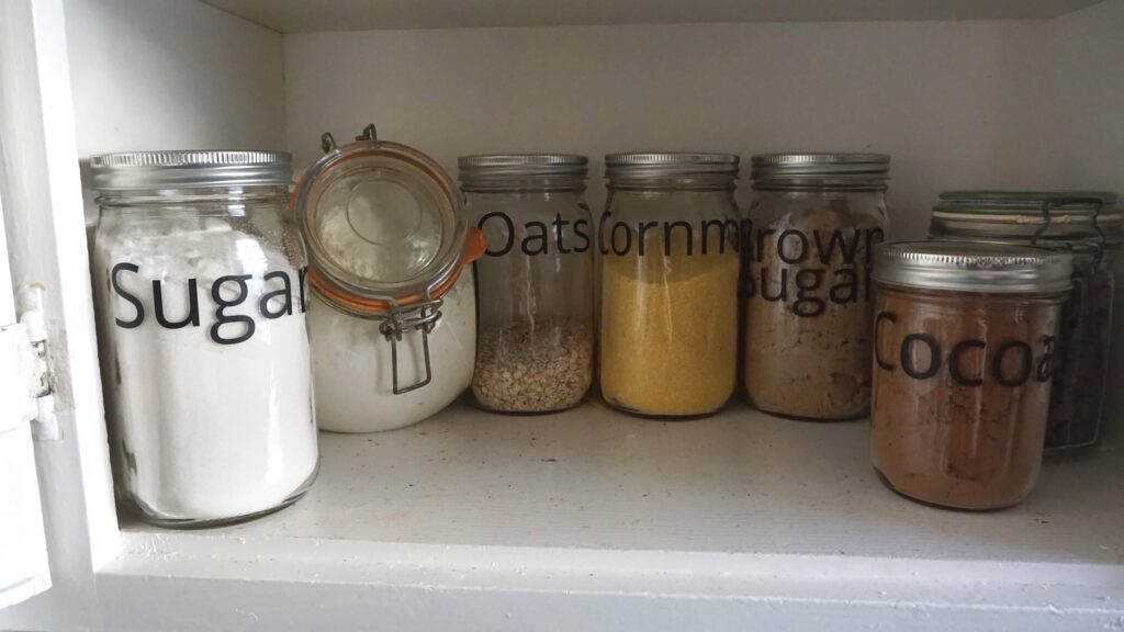 Ball mason jars used as organization for pantry items like sugar, oats, cornmeal, cocoa, and brown sugar. 
