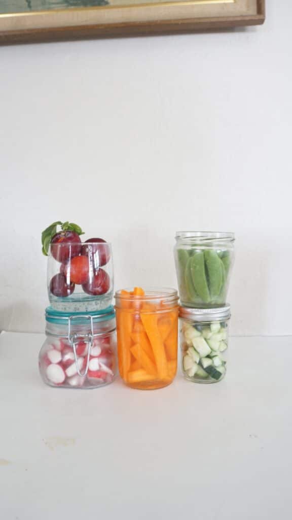 Mason jar uses for storage - carrots, sweet peas, cut cucumbers, radishes, and plums stored in mason jars. 