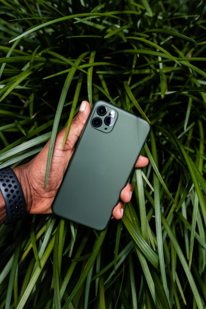 A hand holding a green compostable phone case