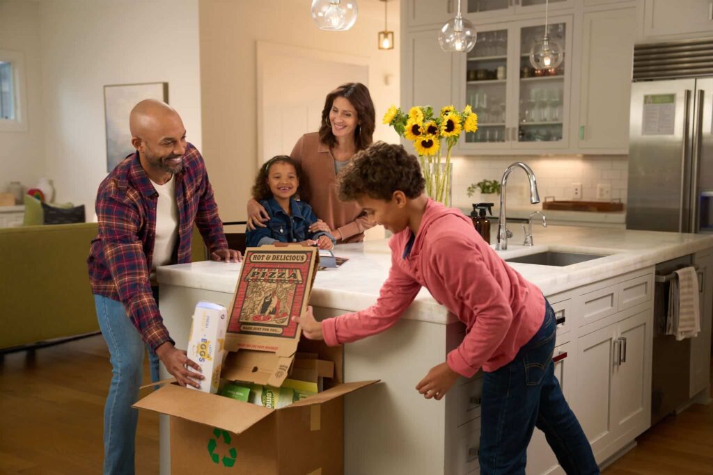 A family placing cardboard in a recycle box in a post with recycling tips