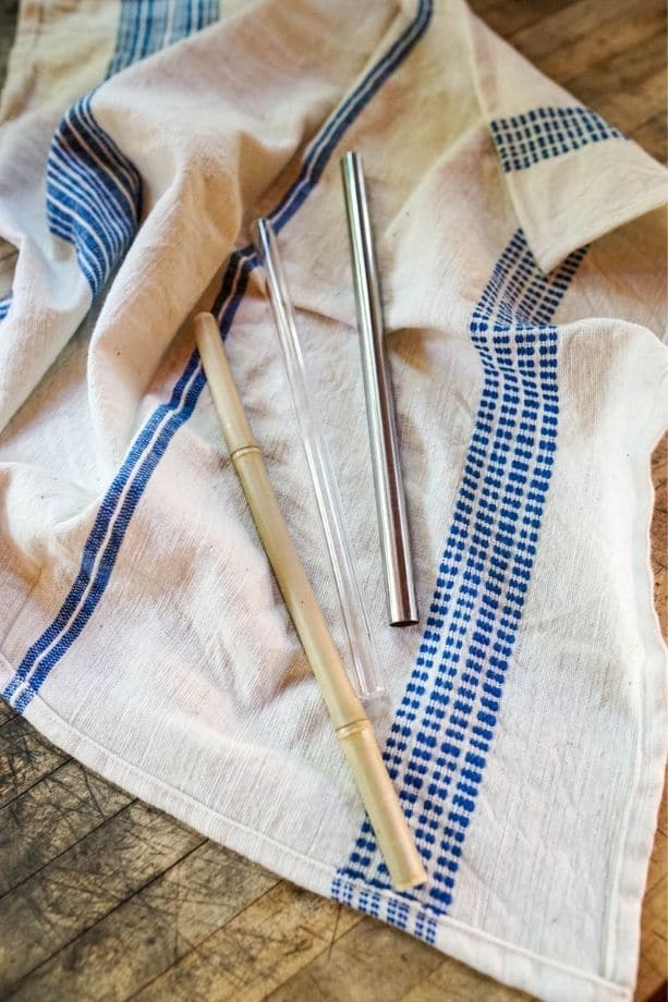 Dish towel with a metal, bamboo, and glass drinking straw laid out on it