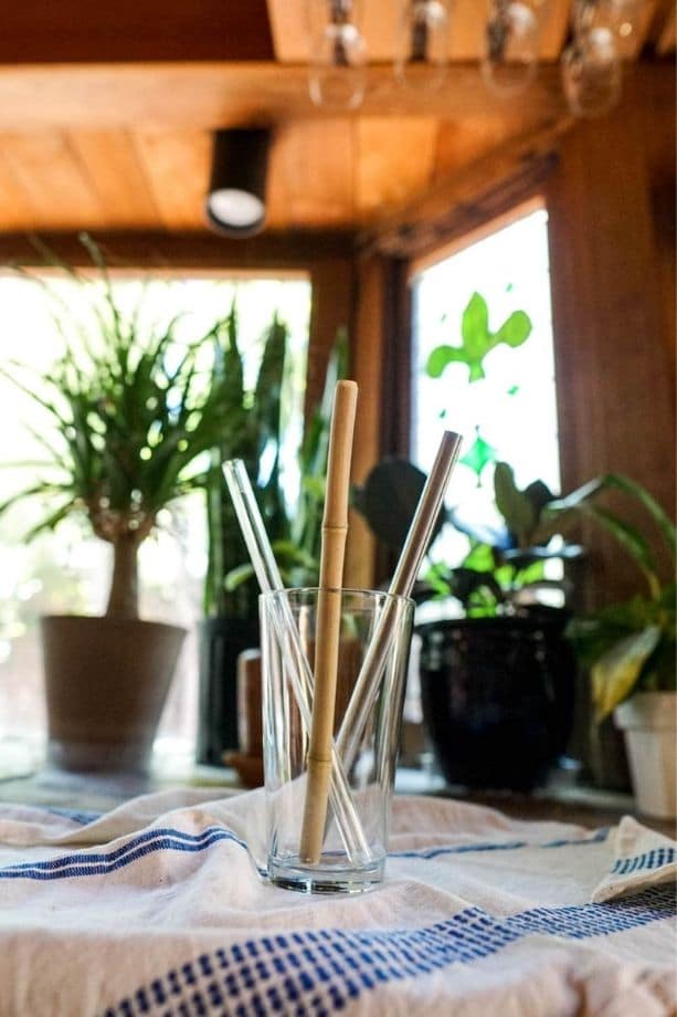 Glass cup with various kinds of non disposable drinking straws in it
