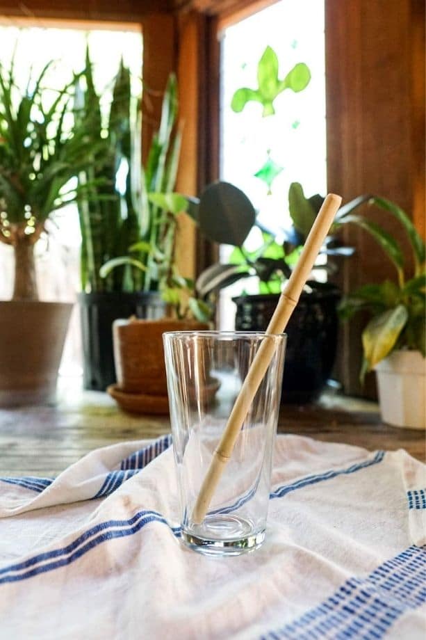 Glass cup with a bamboo straw in it.