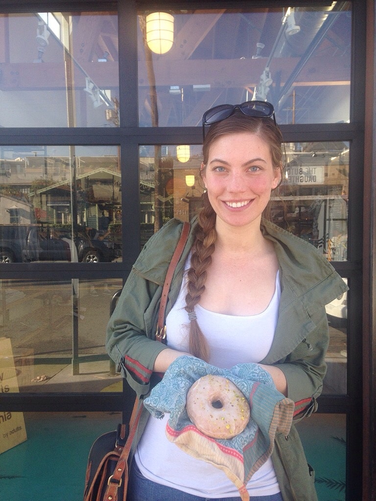 A woman holding a bagel in a reusable napkin as part of her sustainable travel tips