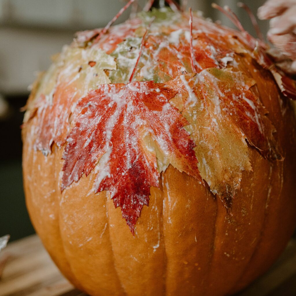A pumpkin covered in fall leaves that were glued on with homemade glue